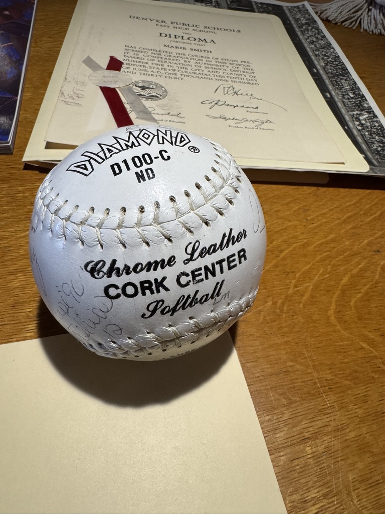 A commemorative East High School softball resting on a framed award certificate