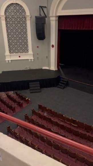 Rows of restored red seats in the East High School auditorium, looking toward the arched side wall