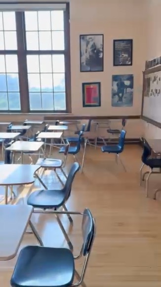 A bright East High School classroom with framed artwork on the wall and worktables in the center